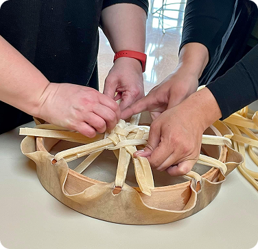 Hands weaving a traditional basket during a cultural arts workshop.